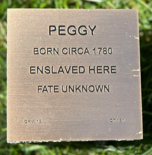 Plaque honoring Peggy, born circa 1780, enslaved, with unknown fate. Historical remembrance and solemn tribute.