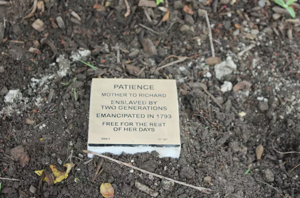 Plaque on soil honoring Patience, emancipated in 1793, symbolizing freedom from generations of enslavement.
