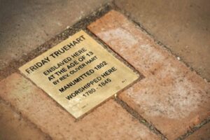 Memorial plaque for Friday Truehart, enslaved at 13, manumitted in 1802, worshipped from 1780-1845 on a brick pathway.