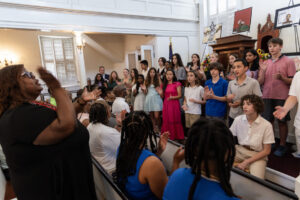 A choir of diverse children sings enthusiastically in a church, surrounded by an audience, capturing joyful harmony.