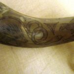Intricately carved animal motifs on a wooden ceremonial horn with distinctive designs.