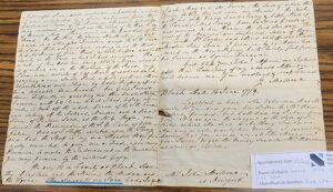 Handwritten 1779 letter on aged paper with historical content, displayed on a wooden table.